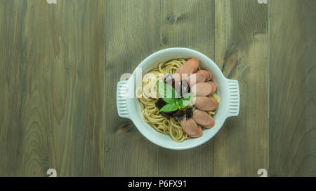 Spaghetti mit Wurst und getrocknete Paprika, würzig und scharf auf hölzernen Hintergrund, Ansicht von oben Stockfoto