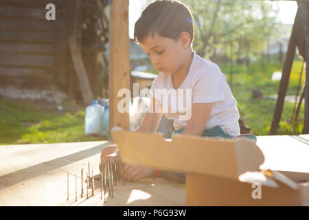 Junge Hammer Nägel mit dem Hammer in einem Holzbrett Stockfoto