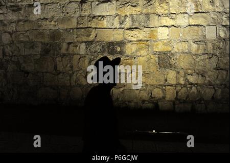 Hintergrundbeleuchtung Aussicht auf die Silhouette der Kopf eines orthodoxen Juden wandern entlang der Mauern der alten Stadt. Jerusalem. Israel. Stockfoto