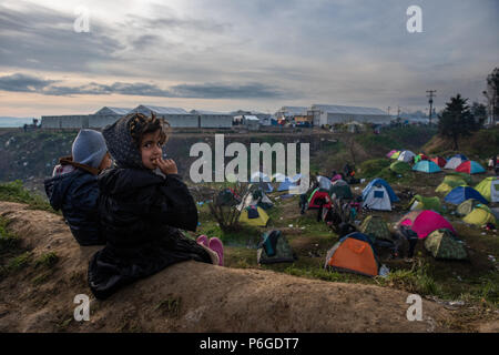 Flüchtlingskinder sitzen auf dem Hügel und beobachten das Leben in den behelfsmäßigen Lager der Greek-Macedonian Grenze in der Nähe des griechischen Dorf Idomeni. Stockfoto