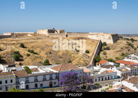 Häuser von Castro Marim und einem Ausblick auf die mittelalterliche Festung auf dem Hügel mit dem gleichen Namen, durch die Schutzmauer umgeben. Strahlend blauen Himmel. Castro Mar Stockfoto