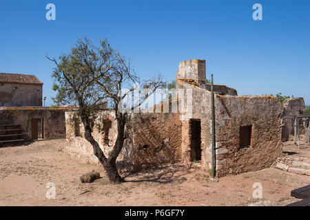 Details der Architektur der Ruine der Burg Castro Marim, Algarve, Portugal. Alter Baum neben dem Haus. Strahlend blauen Himmel. Stockfoto