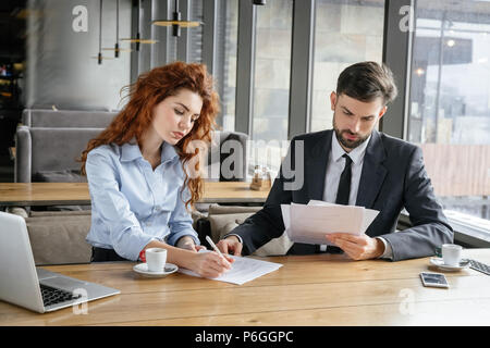 Mann und Frau in Business Lunch im Restaurant am Tisch Teamarbeit Erfüllung Dokumente ernst Sitzen konzentriert Stockfoto