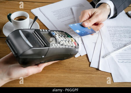 Geschäftsmann auf Business Lunch im Restaurant am Tisch für den Kaffee bezahlen mit Kreditkarte in der Nähe sitzen - mit Maschine Stockfoto