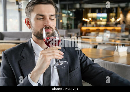 Geschäftsmann auf Business Lunch im Restaurant sitzen am Tisch halten Glas duftender Rotwein freudige geschlossenen Augen schließen Stockfoto
