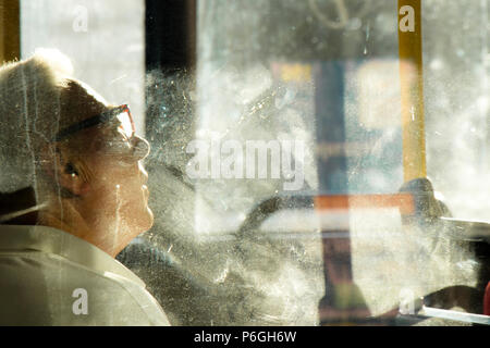 Belgrad, Serbien - Mai 29, 2018: Ältere Menschen sitzen und Tag träumen auf einen Platz am Fenster mit einem Bus an einem Frühlingstag mit Reflexionen und Blu Stockfoto