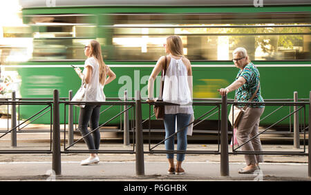 Belgrad, Serbien - Juni 1, 2018: Drei blonde Frauen stehen an der Bushaltestelle und wartet auf die öffentlichen Verkehrsmittel an einem sonnigen Frühlingstag mit Unschärfen und Stockfoto