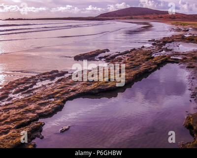 Rosa Playa de Las Americas. Sonnenuntergang auf dem Wasser im Meer und die Felsen reflektieren. Teneriffa, Kanaren, Spanien. Stockfoto