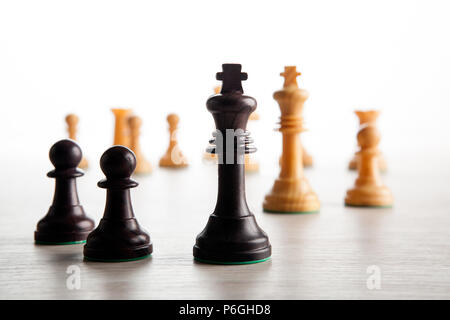 Schwarz chess Bauern auf einem Schachbrett und eine schwarze chess King einen weißen Hintergrund Stockfoto