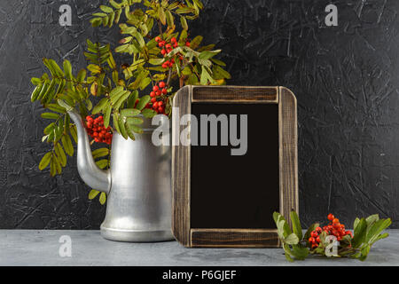 Rowan Niederlassungen in Metall alte Kaffeekanne und Schwarze Schiefertafel auf dunklem Hintergrund Stockfoto