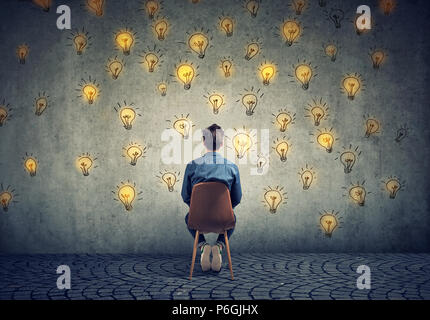 Mann sitzt auf einem Stuhl hat viele Ideen bei der Wall Entscheidungen suchen Stockfoto
