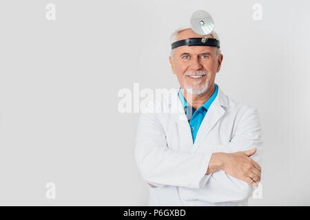 Lächelnd HNO-Arzt, älterer Mann mit Kamera während der ständigen weißen Hintergrund Stockfoto