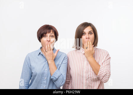 Porträt einer Zwei überrascht Frauen reife Mutter und Tochter stehen über grauen Hintergrund und Stockfoto