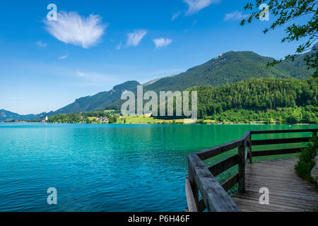 See namens Wolfgangsee in Österreich mit Fußgängerbrücke auf der Seite und die Berge im Hintergrund mit Wolken am Himmel Stockfoto