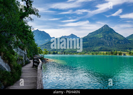 See namens Wolfgangsee in Österreich mit Fußgängerbrücke auf der Seite und die Berge im Hintergrund mit Wolken am Himmel Stockfoto