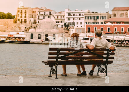 Chania, Griechenland - 14. Juni 2018: ein älteres Ehepaar Rest nehmen und auf der Bank am Rande des Meeres beobachten in einem antiken Teil der schönen Stadt Stockfoto
