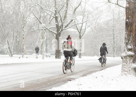 Eine Frau Radfahren in der Amsterdam Vondelpark an einem verschneiten Wintertag im Dezember in den Niederlanden. Stockfoto