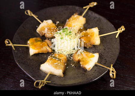 Gegrillter schweinebauch am Spieß serviert. Das Gericht verfügt über asiatische Gewürze.. Stockfoto