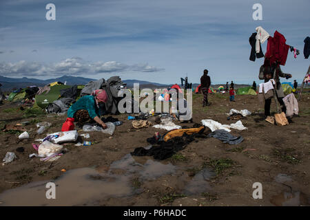 Frau tun Die laundryon auf ein schlammiges Feld nach starken Regenfällen, die in der Nacht an der provisorischen Flüchtlingslager der Greek-Macedonian Grenze Nea fällt Stockfoto