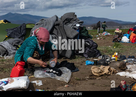 Frau tun Die laundryon auf ein schlammiges Feld nach starken Regenfällen, die in der Nacht an der provisorischen Flüchtlingslager der Greek-Macedonian Grenze Nea fällt Stockfoto