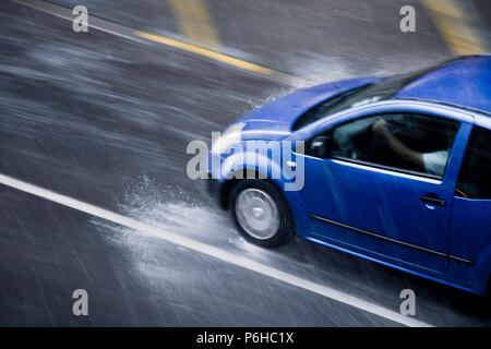Blurry Auto in der Straße, die von der Schwere Regen mit Hagel, in regnerischen Saison Frühjahr in motion blur panning Schuß von oben Stockfoto