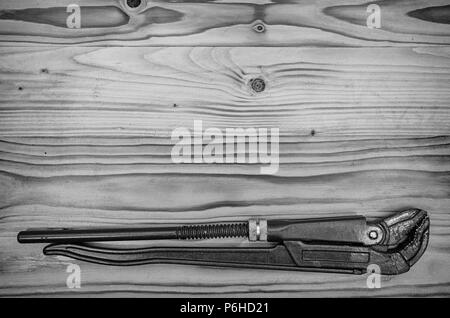 Rohrzange auf einem Holztisch in Schwarz und Weiß. Stockfoto