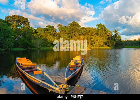 Zwei traditionellen hölzernen Kanus bei Sonnenuntergang im Amazonas Becken mit dem tropischen Regenwald im Hintergrund, Yasuni Nationalpark, Ecuador. Stockfoto