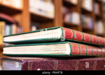 Haufen Vintage Books auf Bibliothek Schreibtisch mit Regal geschlossen Unscharf im Hintergrund Stockfoto