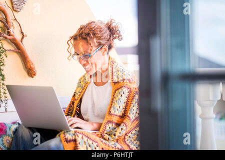 Schöne lächelte kaukasische Frau Arbeit mit einem Laptop im Freien auf der Terrasse. alternative Büro- und Lebensstil zu Hause arbeiten in völlig befreit Stockfoto