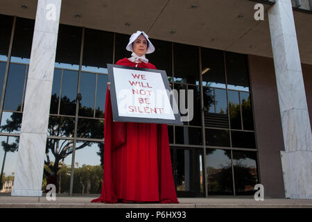 Eine Frau, gekleidet wie eine Magd aus dem Roman und der TV-Serie ist eine Dienerin Trump Verwaltung auf die Familien zusammen März zu protestieren. Stockfoto