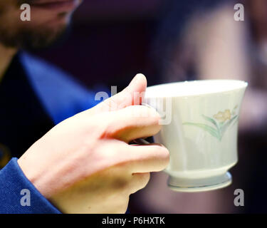 Mann hält Fancy dampfende Teetasse Stockfoto