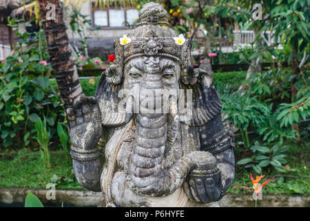 Stein gemeißelt Hindu Ganesha Statue mit Blumen geschmückt. Bali, Indonesien Stockfoto