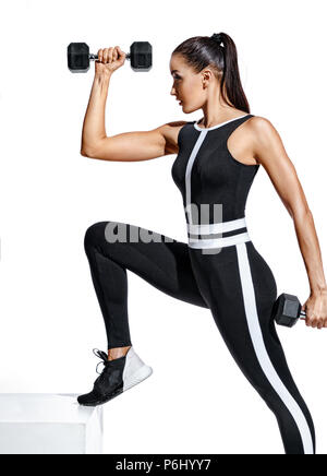 Fitness Mädchen führt das Training mit Hanteln für die Hände. Foto von sportliche Mädchen in Schwarz modische Sportbekleidung auf weißem Hintergrund. Stärke Stockfoto