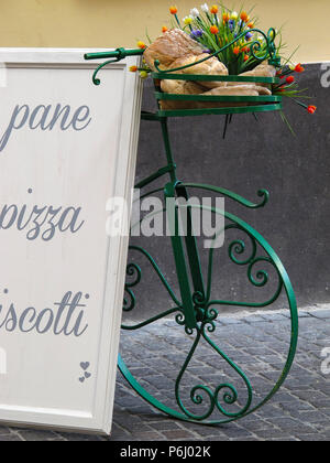 Grüne Fahrrad- und weisses Schild, mit der Aufschrift "Brot, Plätzchen und Pizza", auf einer Straße in Viterbo (Italien) Stockfoto