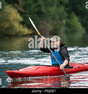 Junge blonde Mädchen schwimmt auf einer Sport Boot Kajak an einem schönen Fluss Stockfoto