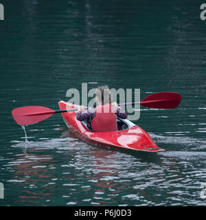 Junger Teenager Girl verwaltet aktiv einen Sport Boot Kajak an einem schönen Fluss Stockfoto