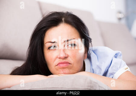 Junge traurige Frau liegend auf ein gemütliches Sofa und Melancholie zu Hause Stockfoto