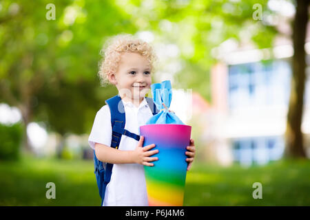 Glückliches Kind Holding traditionelle deutsche candy Kegel auf der erste Schultag. Wenig Kursteilnehmer mit Rucksack und Bücher aufgeregt zurück zu Schule zu werden. Anfang Stockfoto