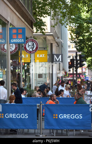 Die Leute draußen sitzen eine Reihe von Cafés und Take-away Läden einschließlich sandwichmaker und Bäckerei Greggs, Mikel Kaffee und Essen. der Tottenham Court Road i Stockfoto