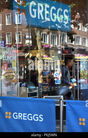 Ein Kunde geht aus dem Take-away Food Shop, Sandwichmaker und Bäckerei Greggs, der Tottenham Court Road im Zentrum von London. Stockfoto