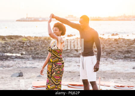 Gerne schön schön schwarz african Race Paar genießen und Tanz am Meer während einer goldfarbenen outdoor Sonnenuntergang. Glück und Freundschaft relationsh Stockfoto