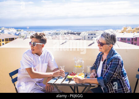 Paar junge und alte Menschen und junge Frau Großmutter und Neffe für Familie Konzept lifestyle Freizeit Aktivität etwas Essen auf der Terrasse auf dem Dach Stockfoto