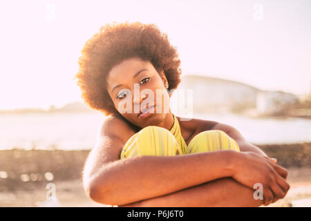 Schöne Haut und Gesicht für schöne blacj Rennen südafrikanische Modell mit alternativen afro Haar. traurig und einsam umarmen sich am Strand mit einem Defokussierten Ozean Stockfoto