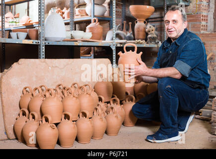 Lächelnd älterer Mann holding Töpferei mit Keramischen Werkstatt Stockfoto