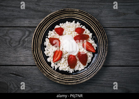 Nützliche Frühstück aus frischen Zutaten: Cornflakes Quark mit Erdbeeren und saure Sahne auf einem Holztisch, Ansicht von oben Stockfoto