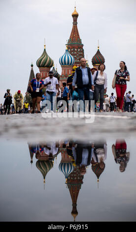 Moskau, Russland. 30. Juni, 2018. Fußball-Weltmeisterschaft. Menschen und die Basilius-kathedrale in einer Pfütze auf dem Roten Platz nieder. Credit: Marius Becker/dpa/Alamy leben Nachrichten Stockfoto