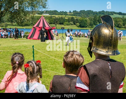 Ritterspiele und mittelalterliche Messe in Linlithgow Palace, Linlithgow, Schottland, Vereinigtes Königreich, 30. Juni 2018. Historische Umfeld Schottland traten weg von ihrer Sommer Unterhaltungsprogramm mit einem fabelhaften Anzeige der Mittelalterlichen Ritterspiele auf dem Gelände des historischen Schlosses. Der Spaß für die ganze Familie Tag enthalten eine lebendige Geschichte Camp und mittelalterliche Spiele. Die historische Saltire Gesellschaft durchführen und eine lebendige mittelalterliche Dorf präsentieren. Zwei Jungen in römischen Soldaten Kostüme und zwei kleine Mädchen gekleidet eine Vorstellung ansehen Stockfoto