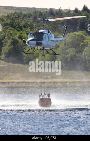 Winter Hill, Bolton, Großbritannien. 30 Jun, 2018. Eine Brandbekämpfung Helikopter sammelt Wasser aus den Quellen Reservoir an der A 675 Belmont Road. Der Hubschrauber gesammelt, um das Wasser und legte es auf das Feuer alle 2-3 Minuten. Quelle: Michael Rawsterne/Alamy leben Nachrichten Stockfoto