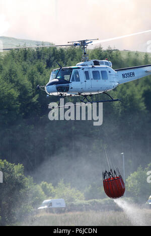 Winter Hill, Bolton, Großbritannien. 30 Jun, 2018. Eine Brandbekämpfung Helikopter sammelt Wasser aus Quellen Behälter neben der A 675, Belmont Road in der Nähe von Bolton. Eine Brandbekämpfung Helikopter sammelt Wasser aus Quellen Behälter neben der A 675, Belmont Road in der Nähe von Bolton. Quelle: Michael Rawsterne/Alamy leben Nachrichten Stockfoto