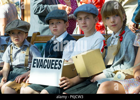 Kidderminster, Großbritannien. 30th. Juni 2018. Eine Zeitreise beginnt mit der Severn Valley Railway, als wir die Uhr auf die 1940s zurückdrehen. Besucher und Mitarbeiter ziehen alle Register, um sicherzustellen, dass ein realistisches Großbritannien aus dem Krieg von WW2 auf dieser historischen Eisenbahnstrecke erlebt wird. 1940s Kinder, die aus dem Zweiten Weltkrieg evakuiert wurden, können hier zusammen auf der Vintage-Station Kidderminster sitzen und auf den nächsten Dampfzug warten sehen. Kredit: Lee Hudson/Alamy Live Nachrichten Stockfoto